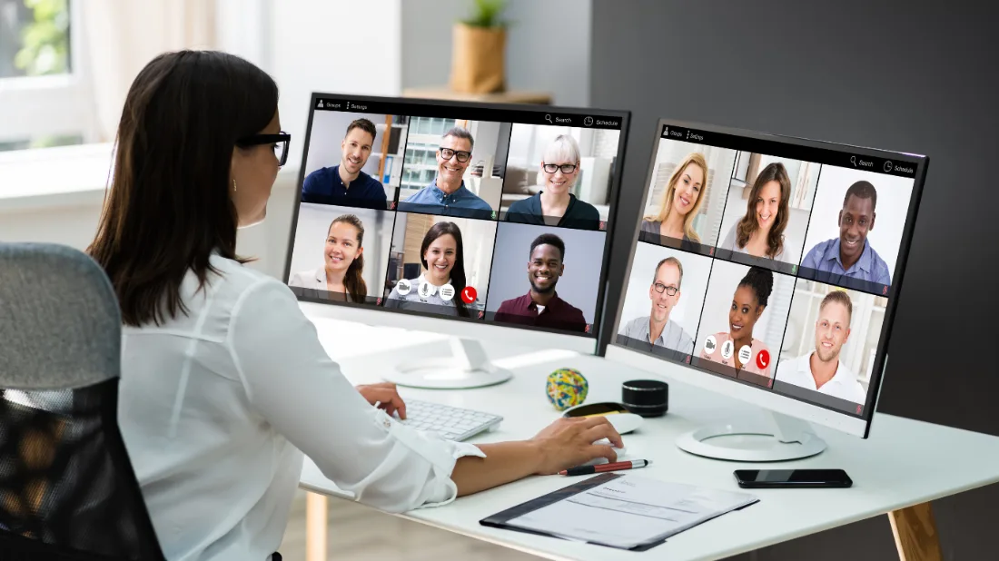Woman sat in front of her computer in a meeting with her colleagues.